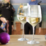 Two wine glasses on a table in front of celebrating divers.